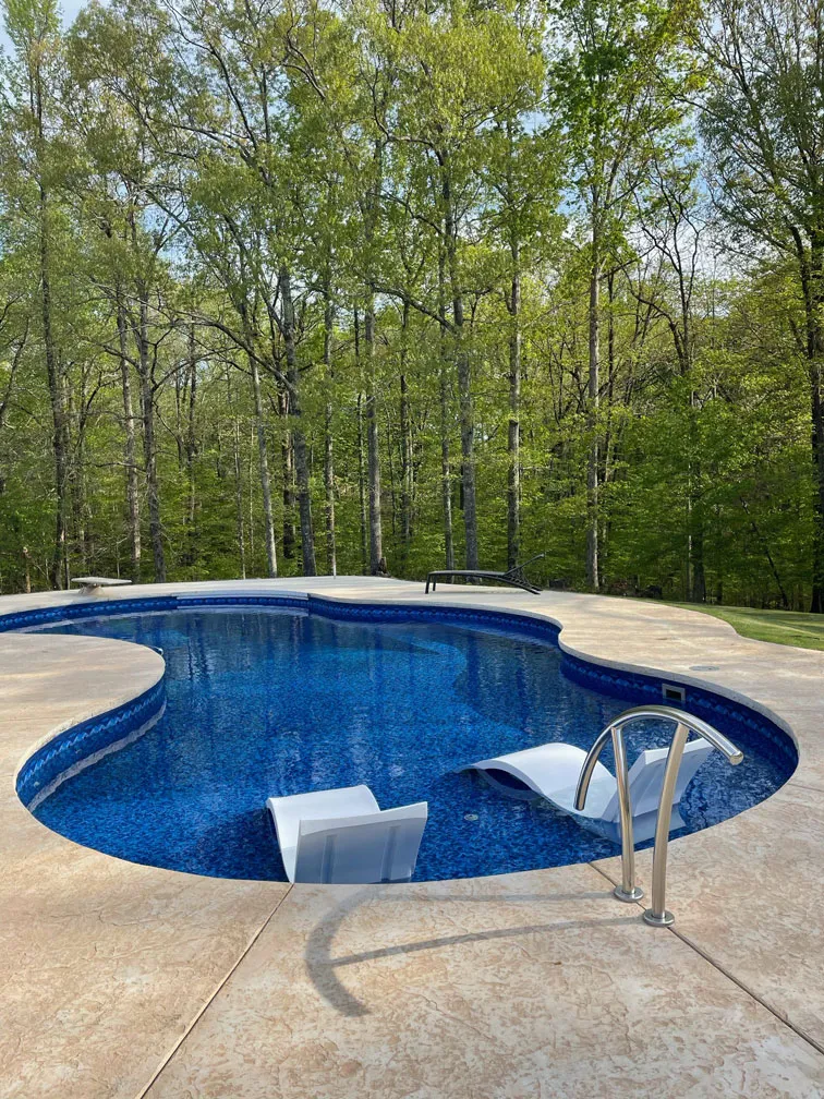 Beautiful freeform inground pool with a wooded backdrop
